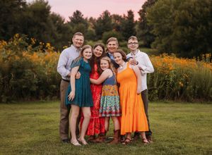 A group poses together outdoors in a field with vibrant orange wildflowers during golden hour.