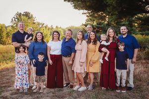 A group poses together outdoors in coordinating burgundy and neutral outfits during golden hour.