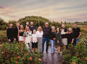 Extended family gathering outdoors in flower garden during sunset.
