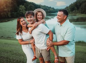 A group enjoying a playful moment together on a grassy hill near a lake.