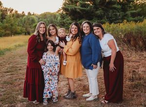 Group photo of friends in coordinating outfits standing together at sunset in a rustic outdoor setting.