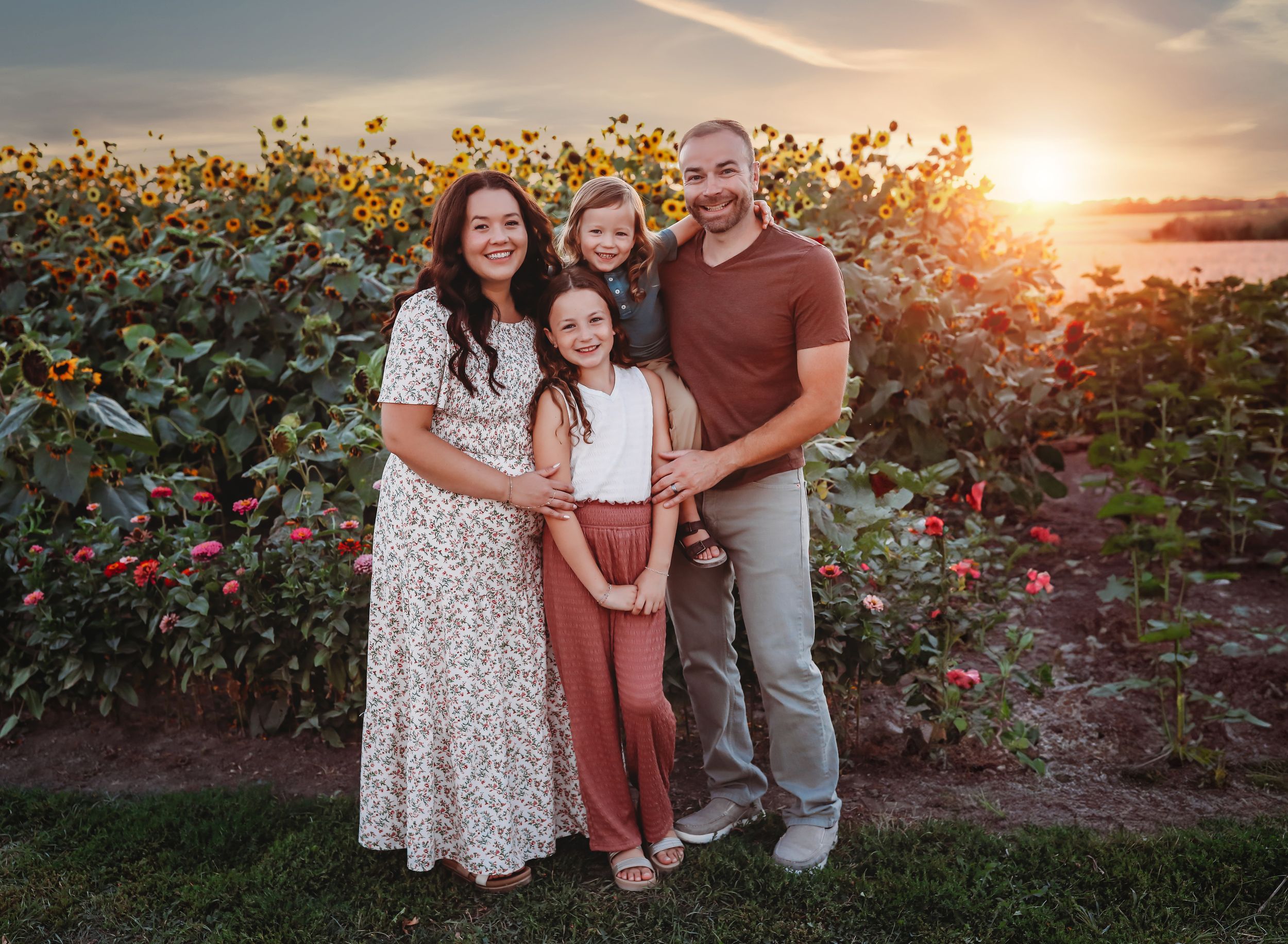Family portrait in a sunflower field during golden hour sunset.