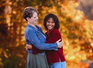 People sharing warm embraces against a backdrop of stunning autumn foliage in golden light.