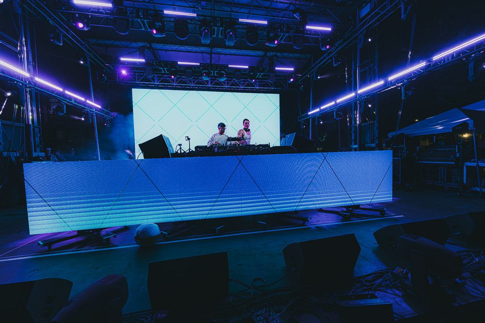 Blue-lit conference venue with large display screens and sleek modern design elements.