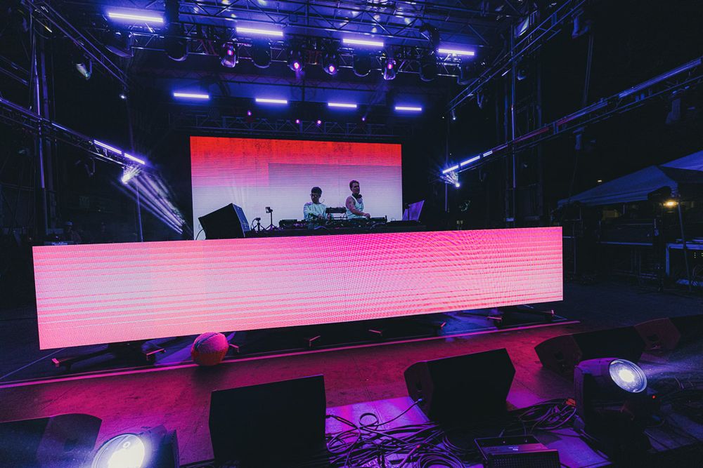 Modern stage design featuring LED screens and dramatic red and purple lighting effects.