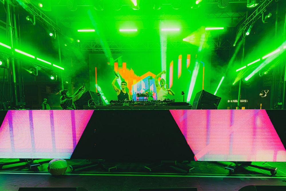 Concert stage setup with pink LED panels and dramatic green lighting effects.