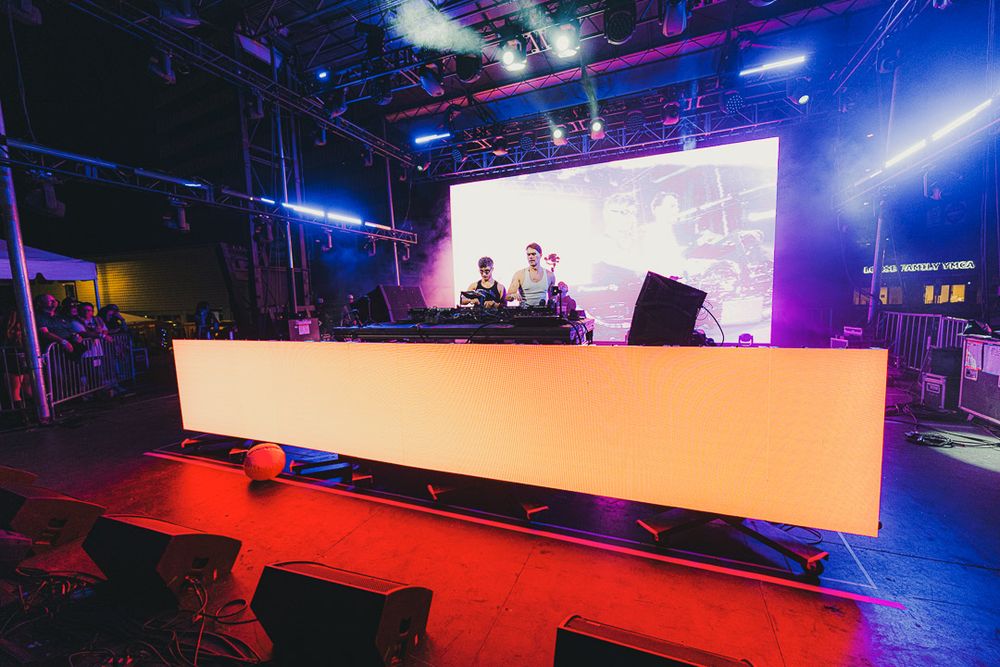 Nightclub performance setup featuring an elevated white booth on red carpet with dramatic stage lighting.