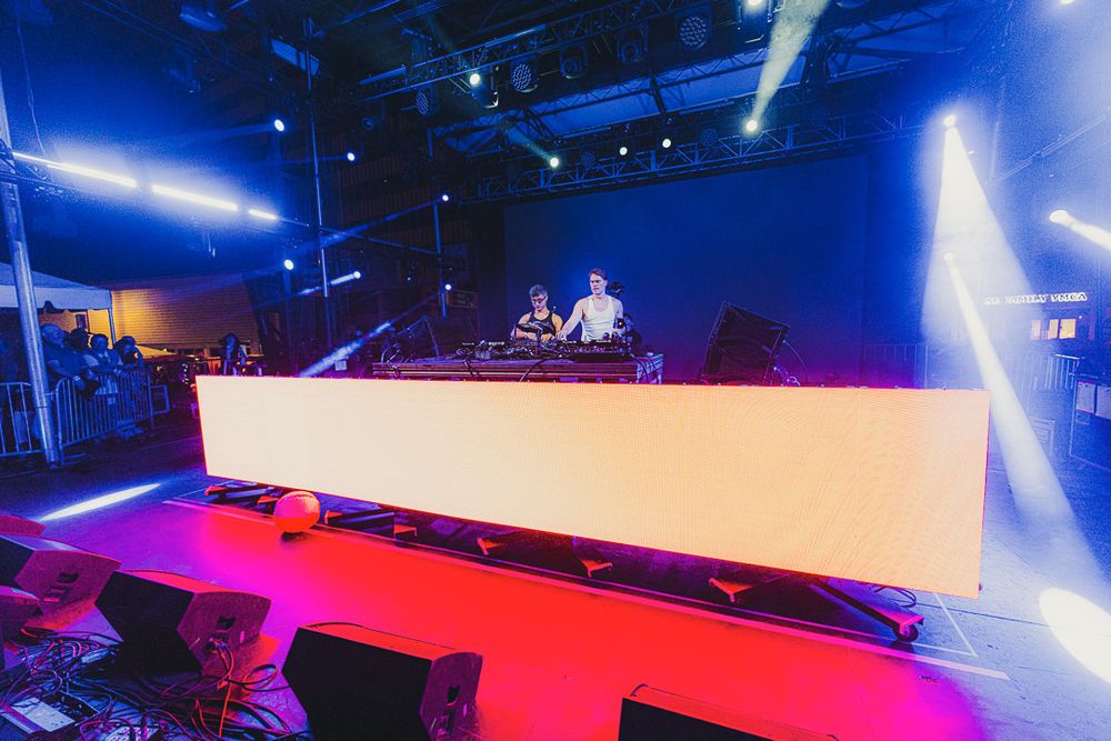 Concert venue with red carpet flooring and blue theatrical lighting creates a dramatic entertainment atmosphere.
