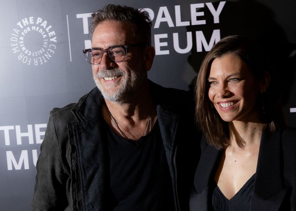 Two people smile together at a Paley Museum event, with one wearing glasses and a black shirt.