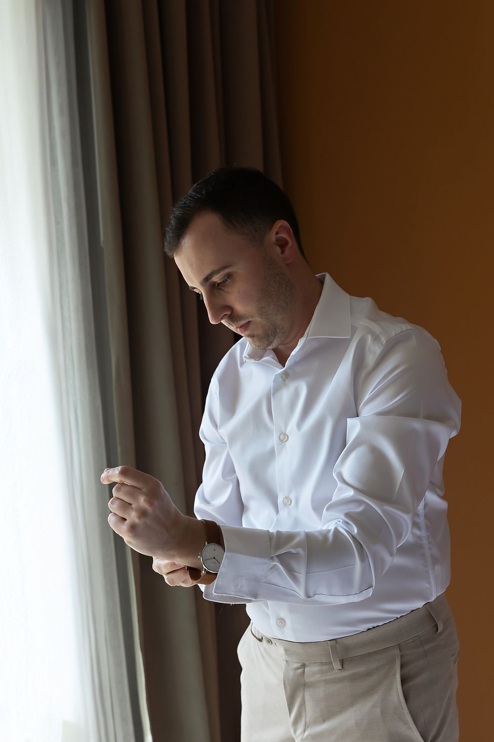 Groom adjusting cufflinks while getting ready at Grand Palladium Riviera Maya.