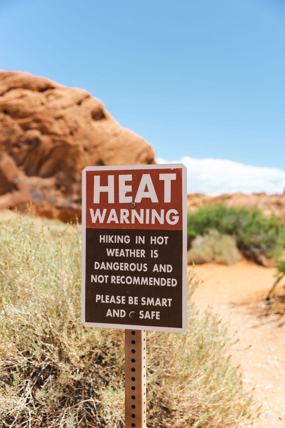 Warning signs about dangerous heat conditions on desert hiking trail.