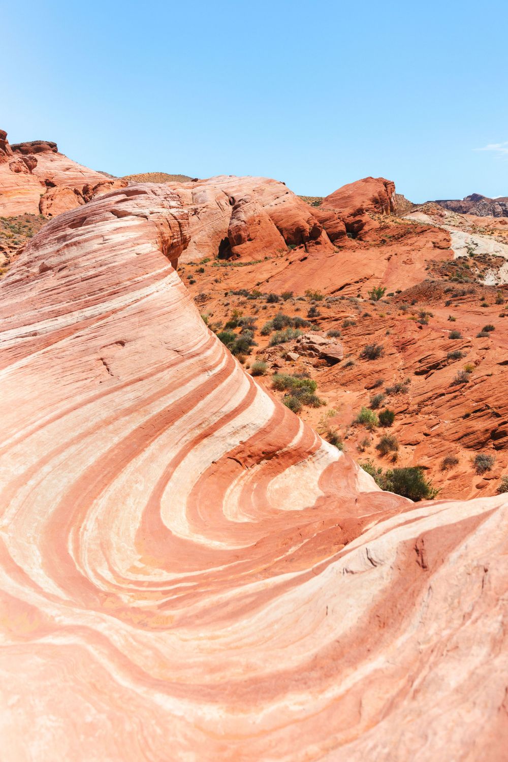 Curved striped patterns in red sandstone formations against blue sky at Valley of Fire State Park.