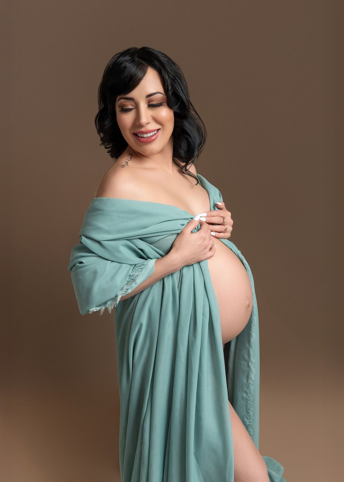 Denver maternity photography session of a pregnant mother wrapped in blue tulle in a private studio.