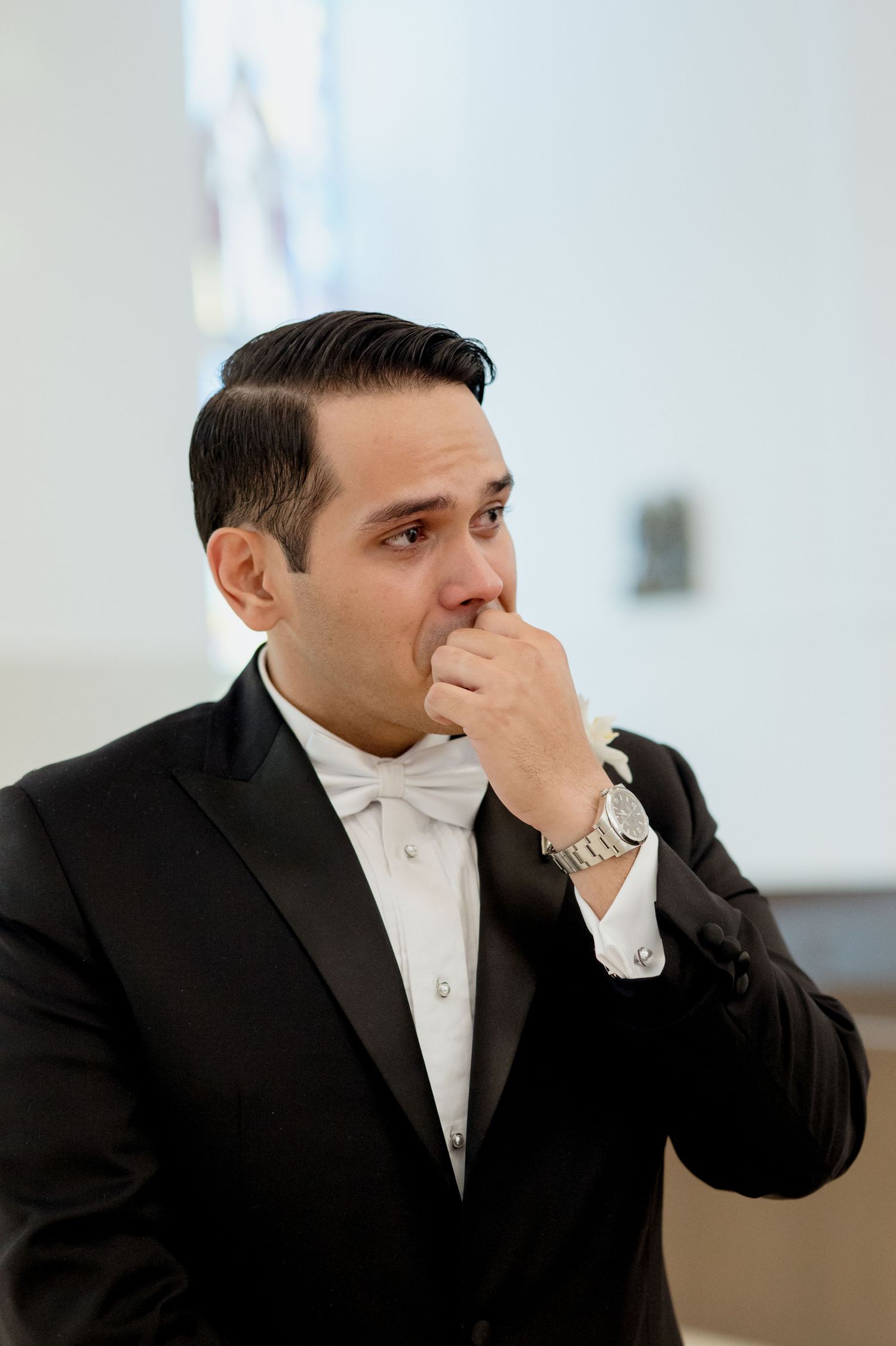 A person in formal attire covering their face while expressing emotion in a sequence of candid shots.
