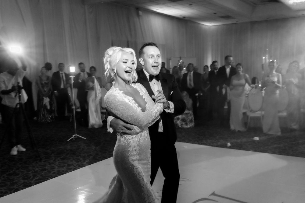 Couples dance together in a dimly lit ballroom during what appears to be a wedding reception or formal event.