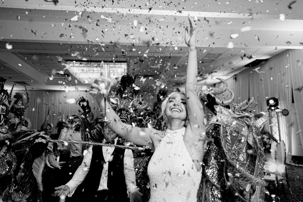 Wedding celebration with confetti falling as guests dance and celebrate on a crowded dance floor during reception.