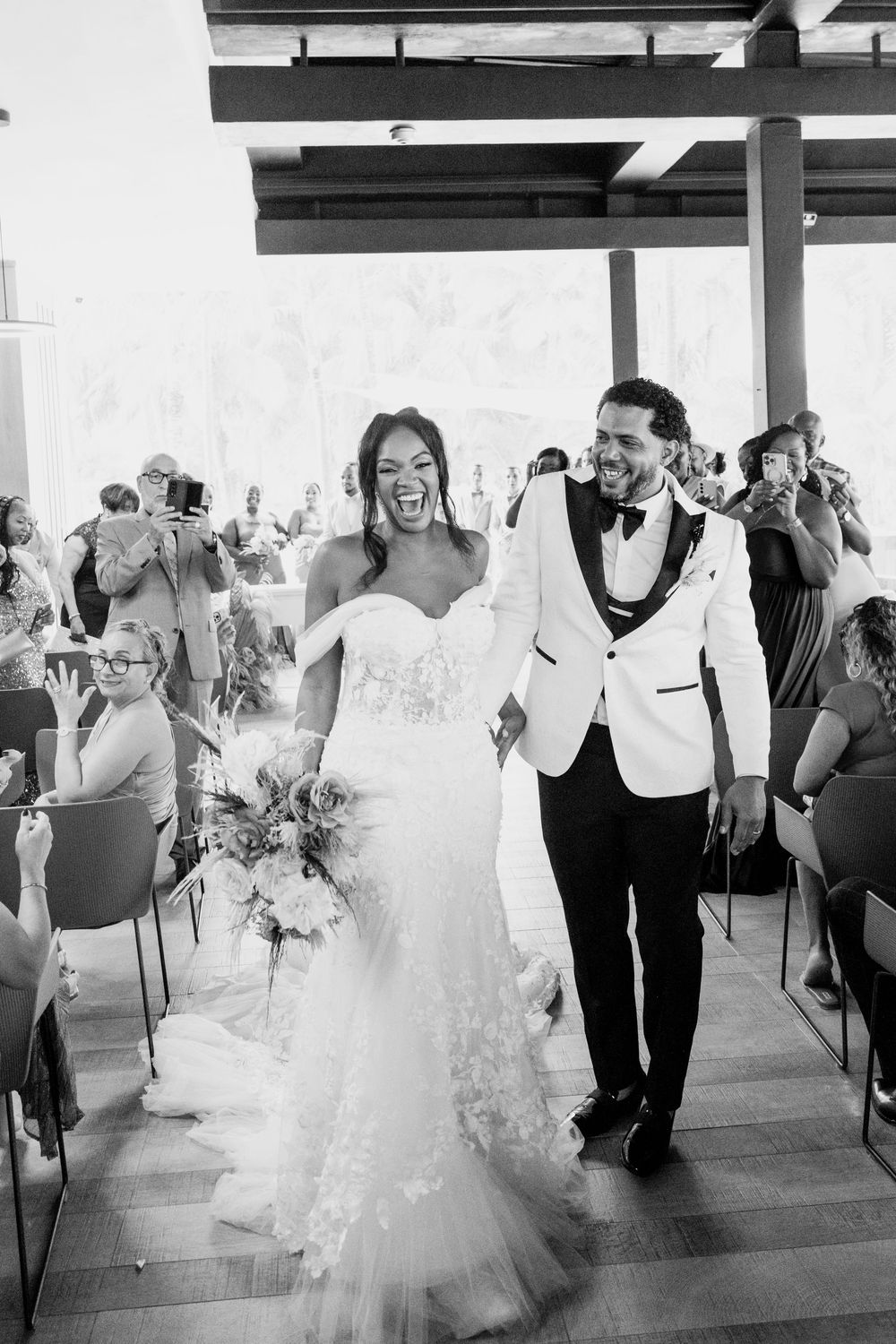 Wedding party dancing and celebrating in a joyful line dance at an indoor reception venue.