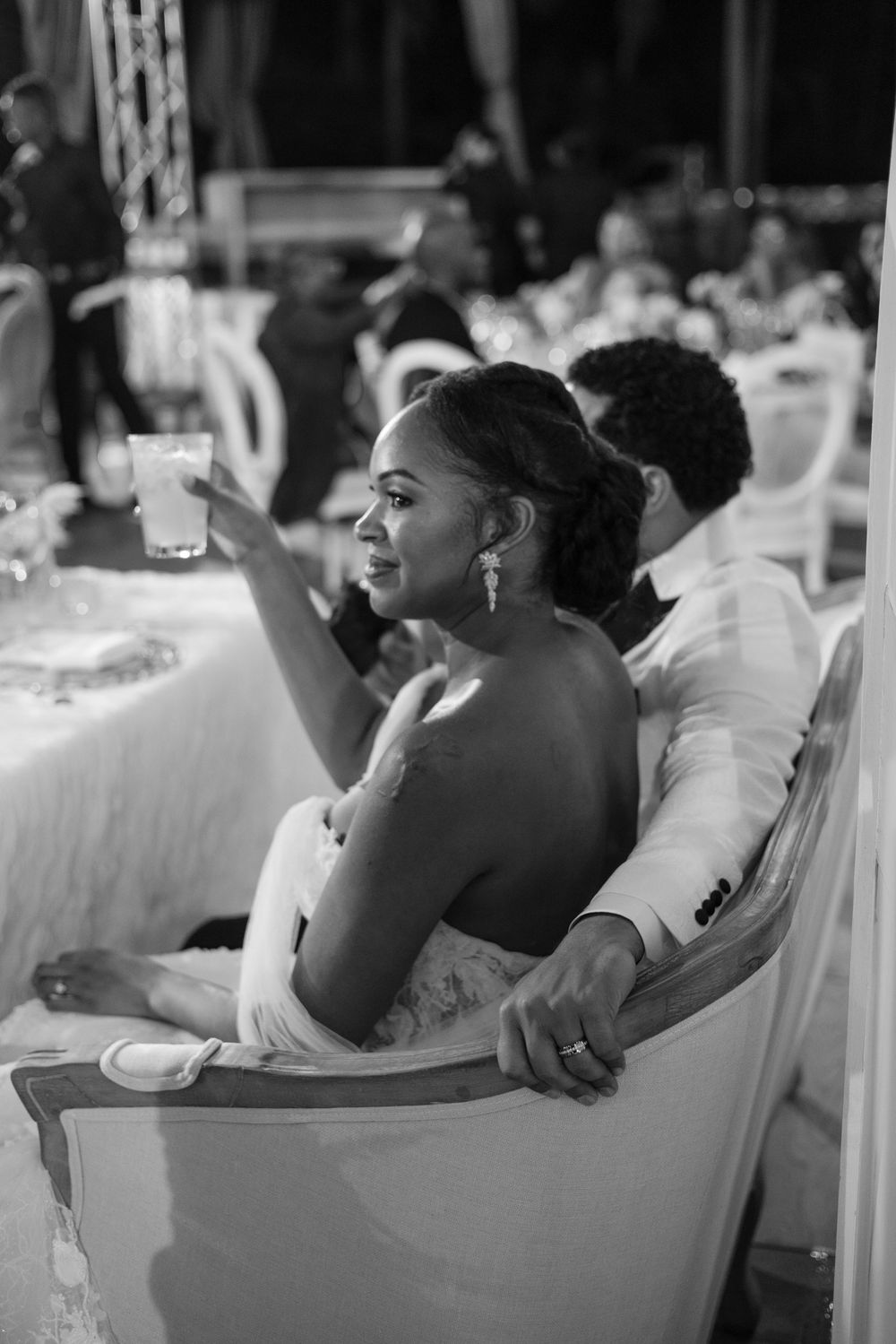 Black and white photo of wedding guests relaxing and socializing on comfortable lounge furniture.