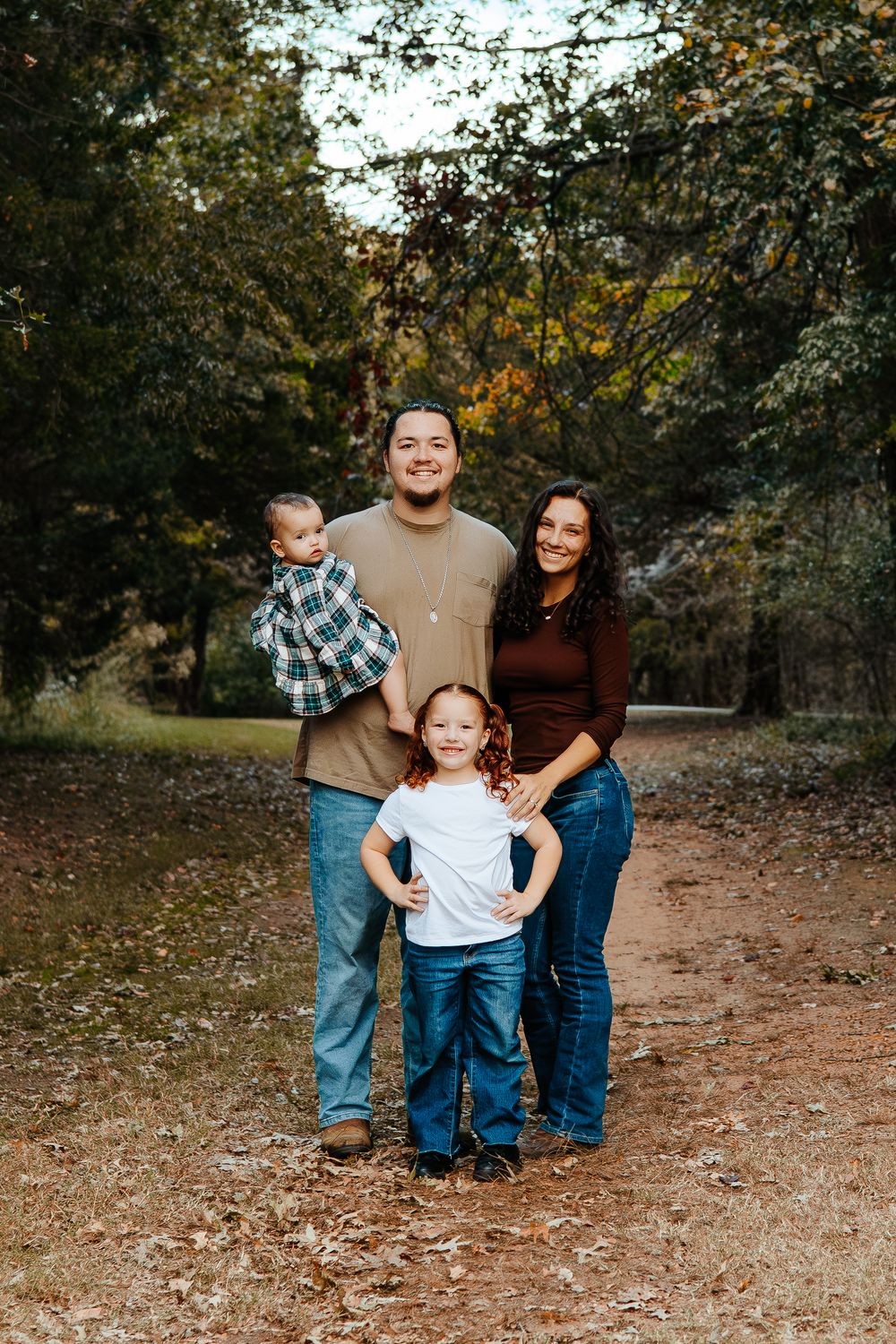 A candid family moment captured on a wooded trail during fall.