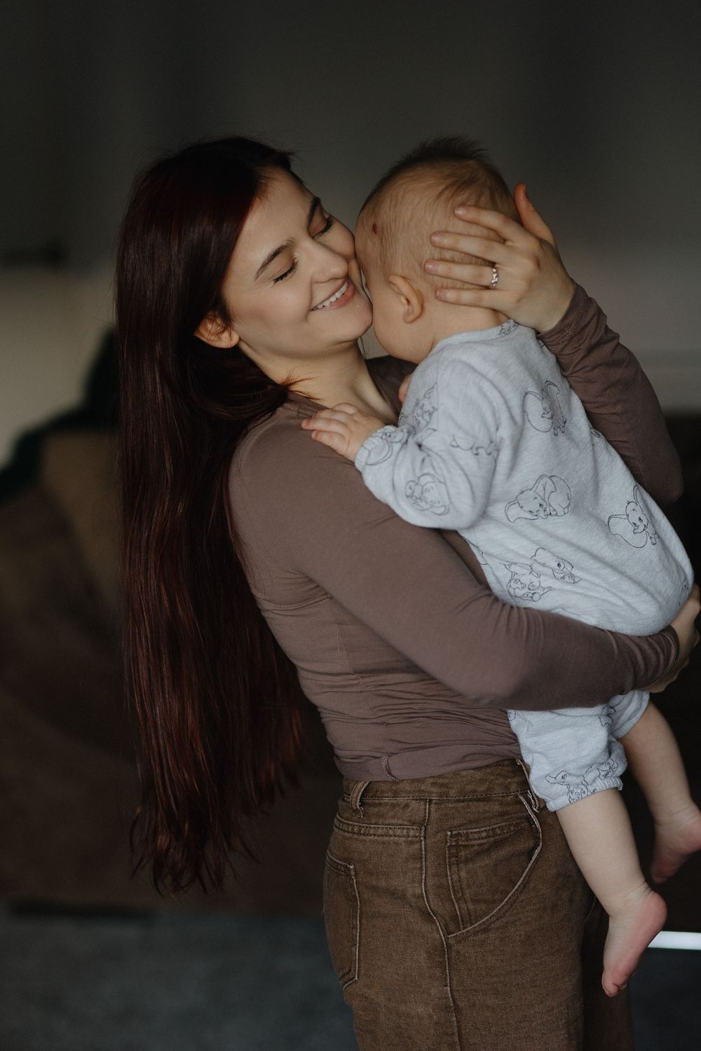 A tender moment between parent and child sharing a joyful embrace in casual brown and grey clothing.