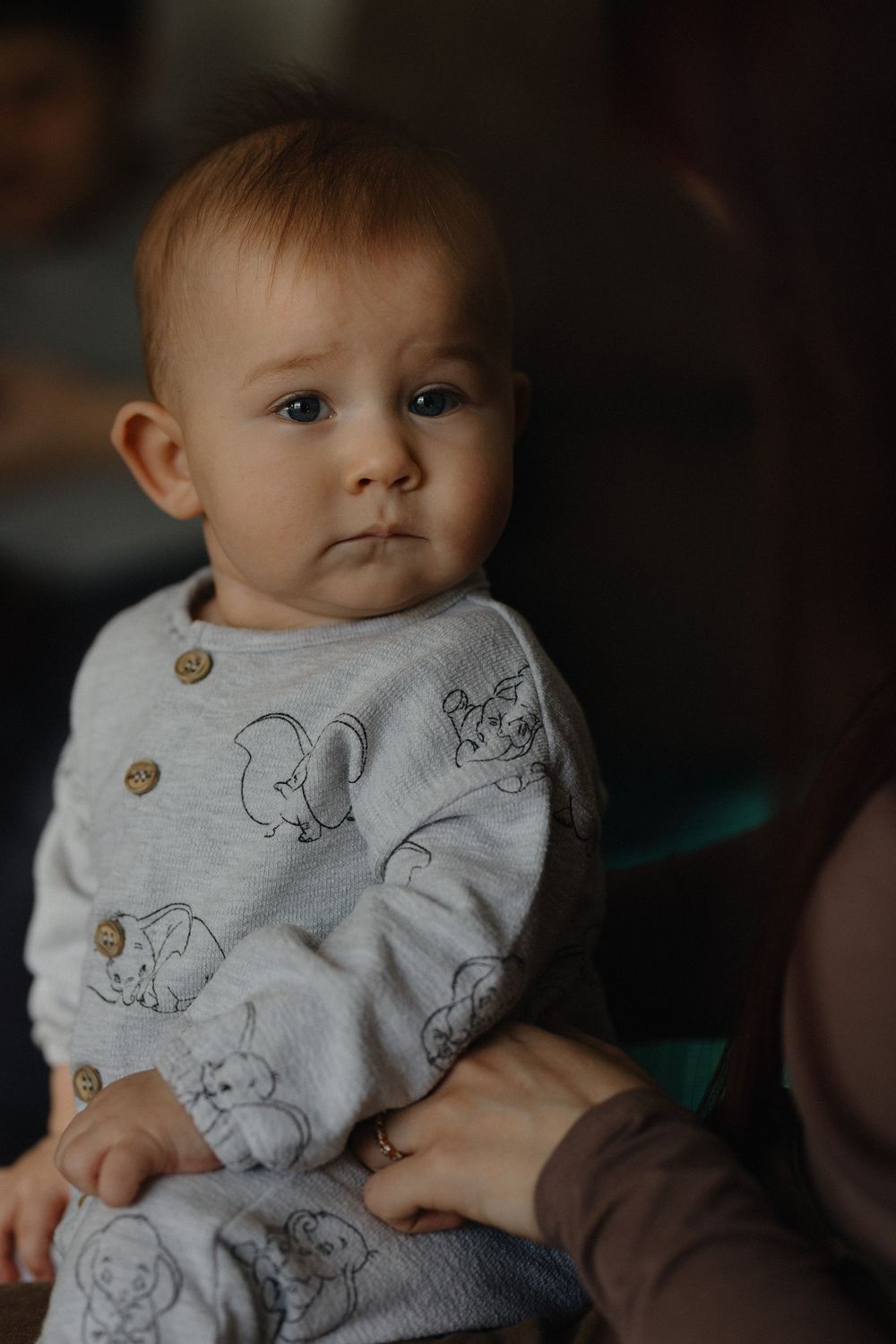 Baby wearing a gray sweater with animal illustrations and wooden buttons in a series of close-up shots.