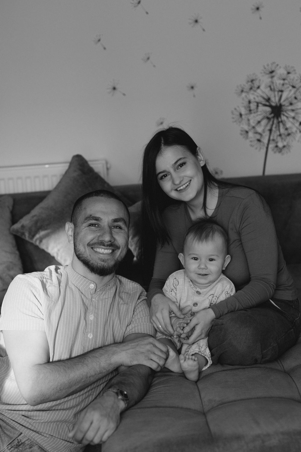 A black and white photo sequence showing a parent and baby lying together on a couch, sharing joyful moments.