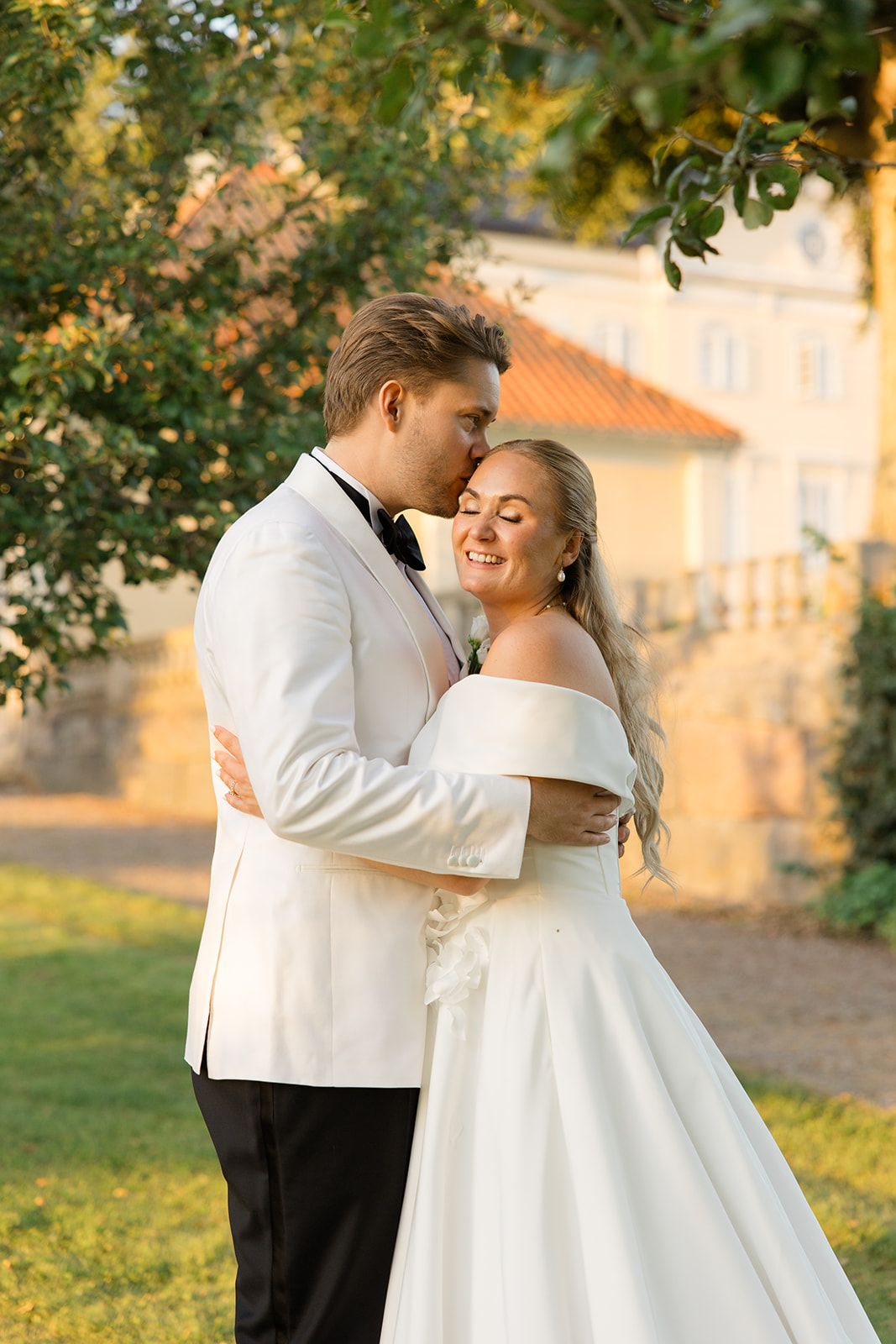 A couple in wedding attire walks through a scenic field at sunset creating silhouettes against the light.