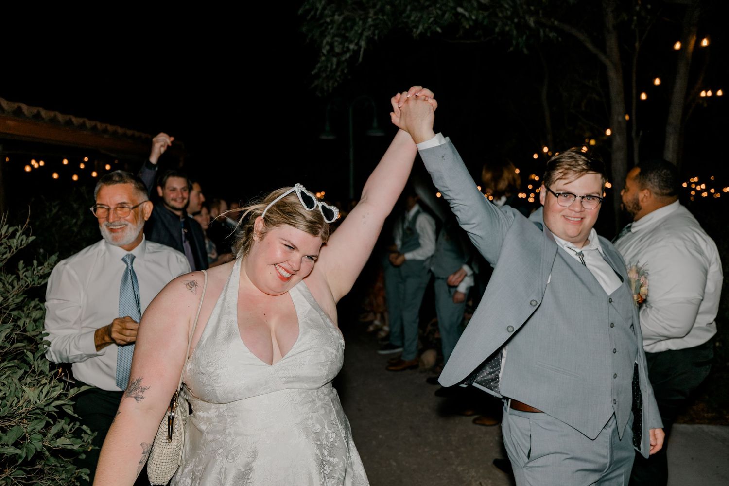 Wedding party guests dance and celebrate with sparklers during a nighttime reception celebration.