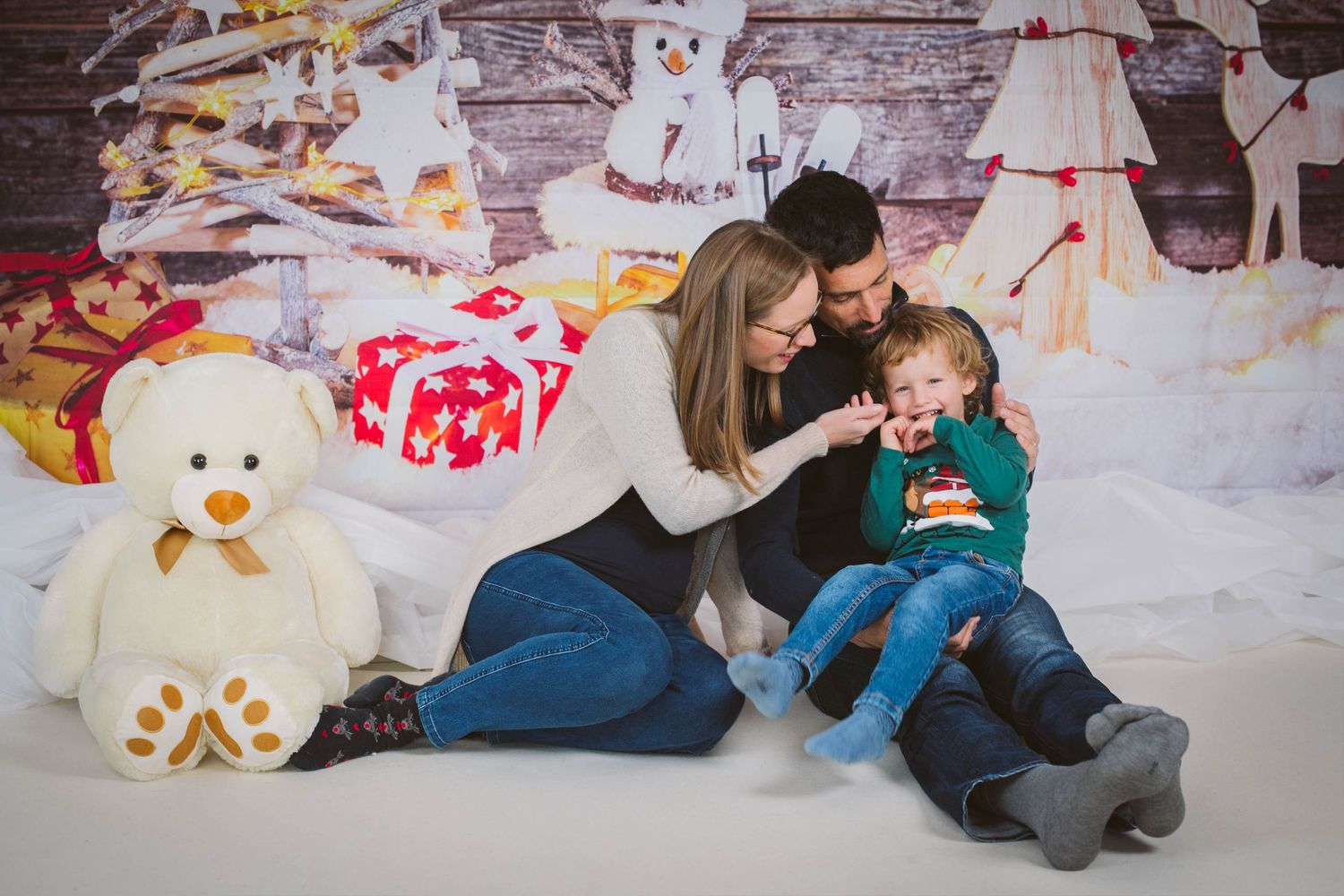 A festive holiday photoshoot with a snowy backdrop, plush toys, and cozy winter decor.
