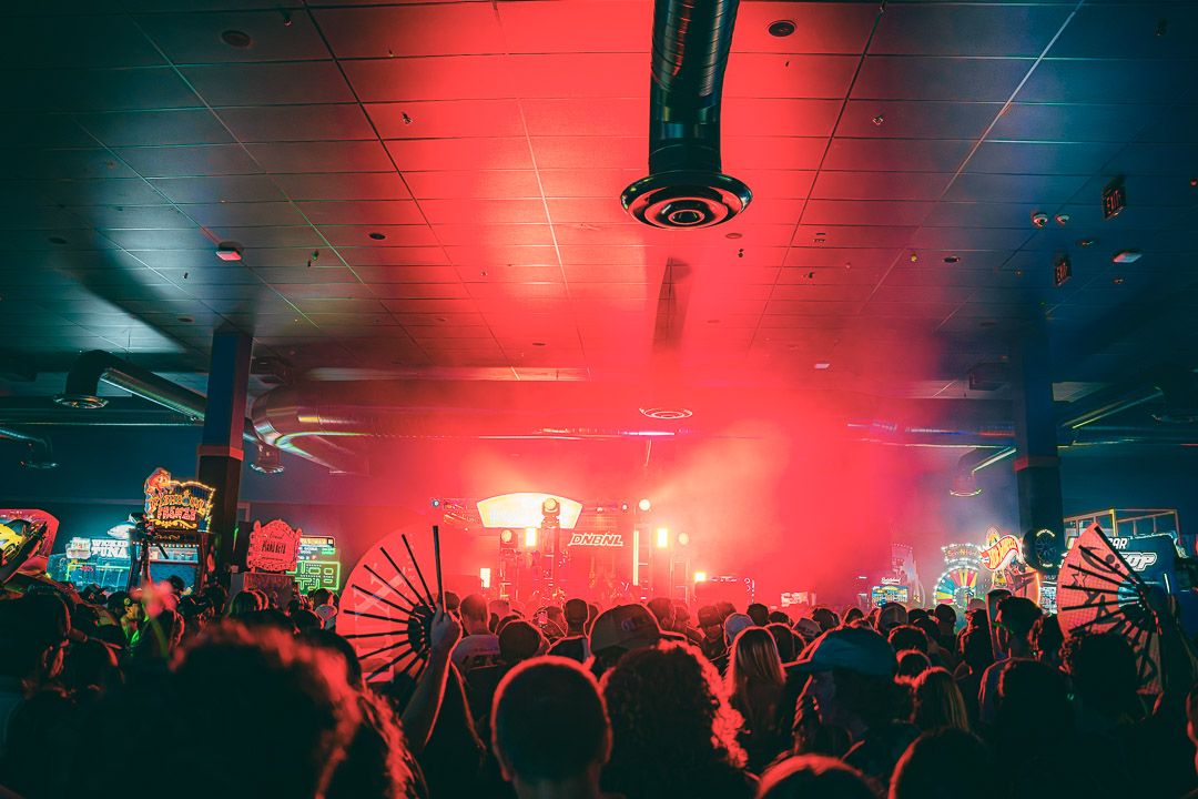 Concert crowd silhouettes against dramatic red and blue lighting during a live performance.