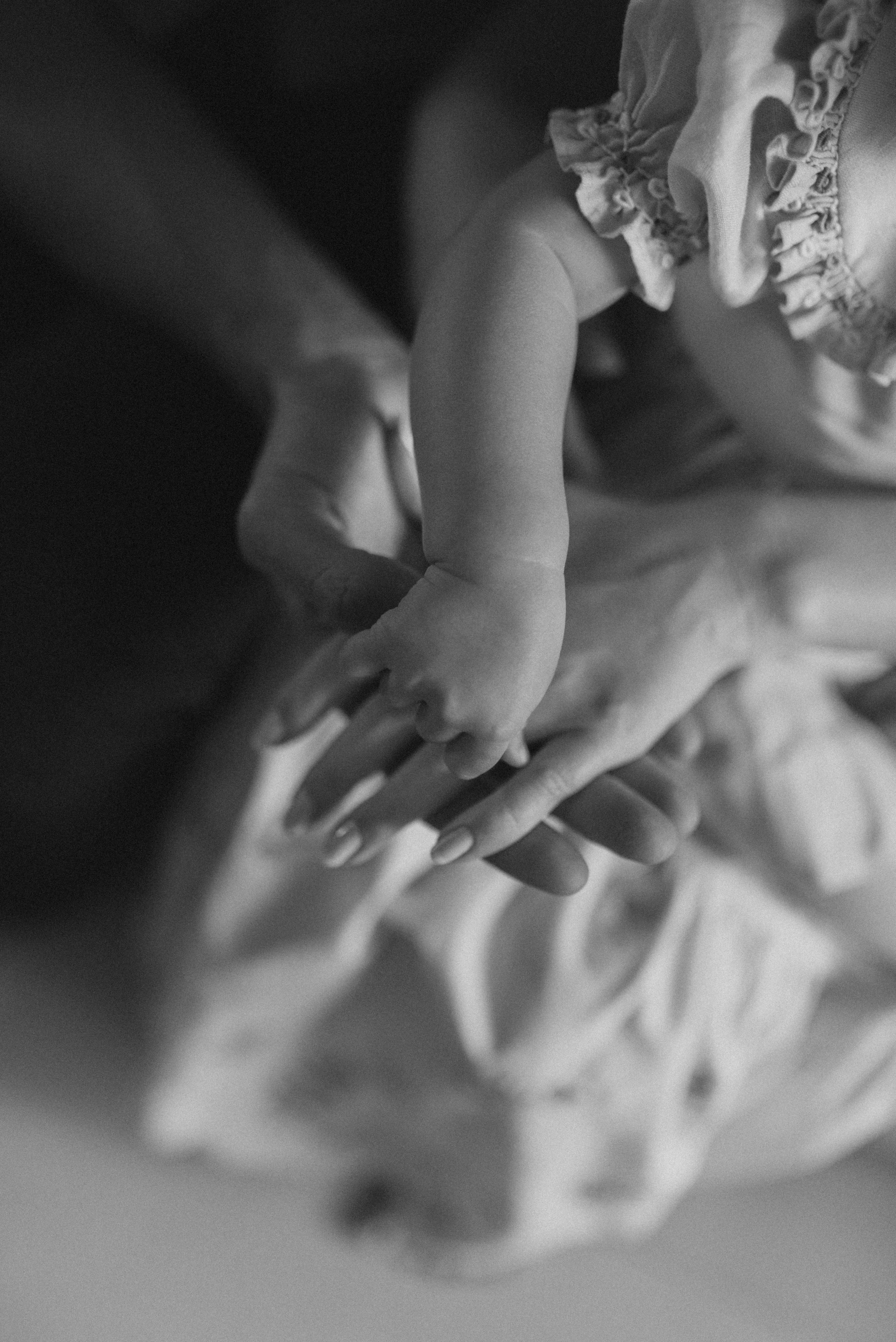Close-up black and white image of a child's hand touching delicate lace fabric.