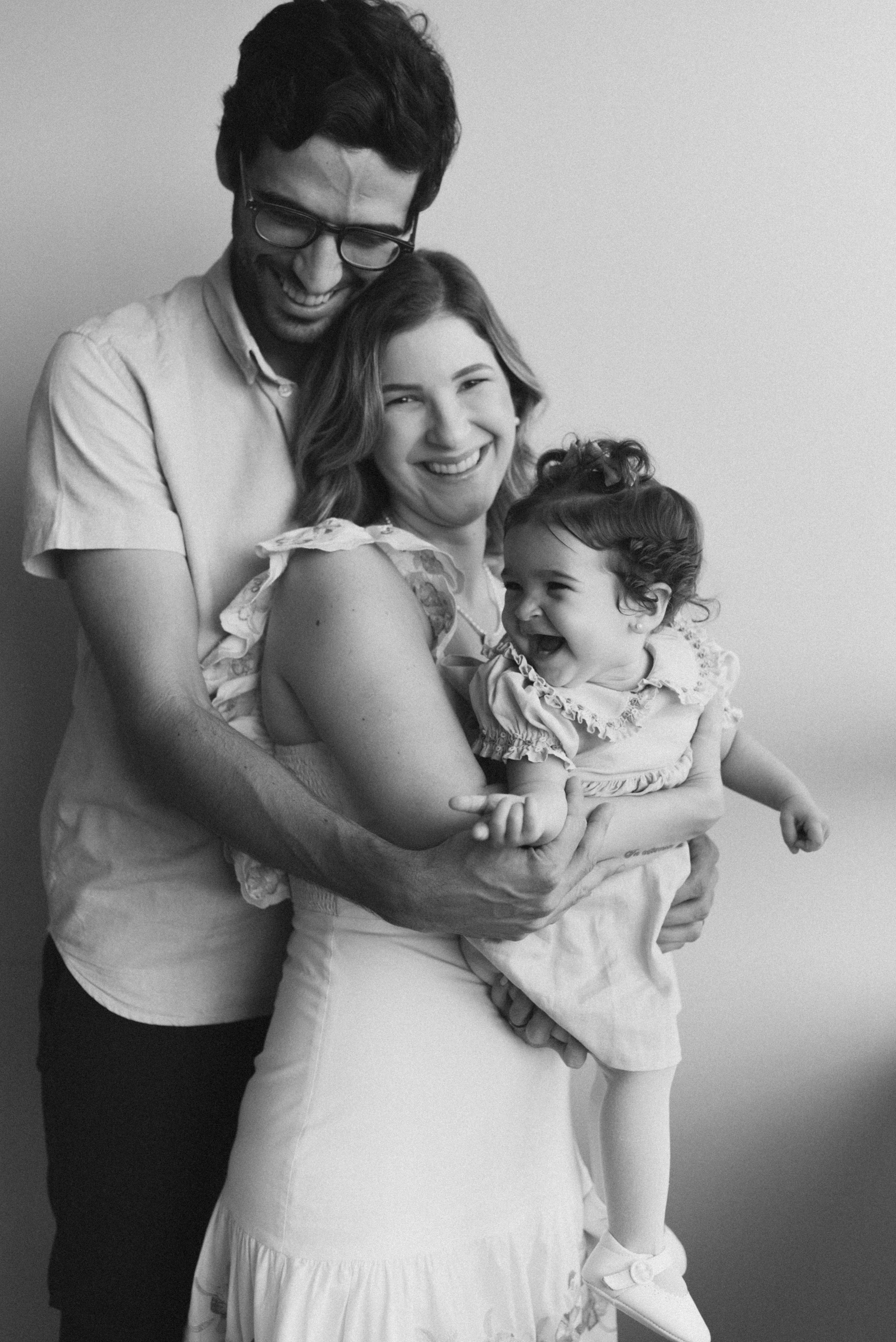 Family portrait showing warm embrace and joyful expressions in black and white.