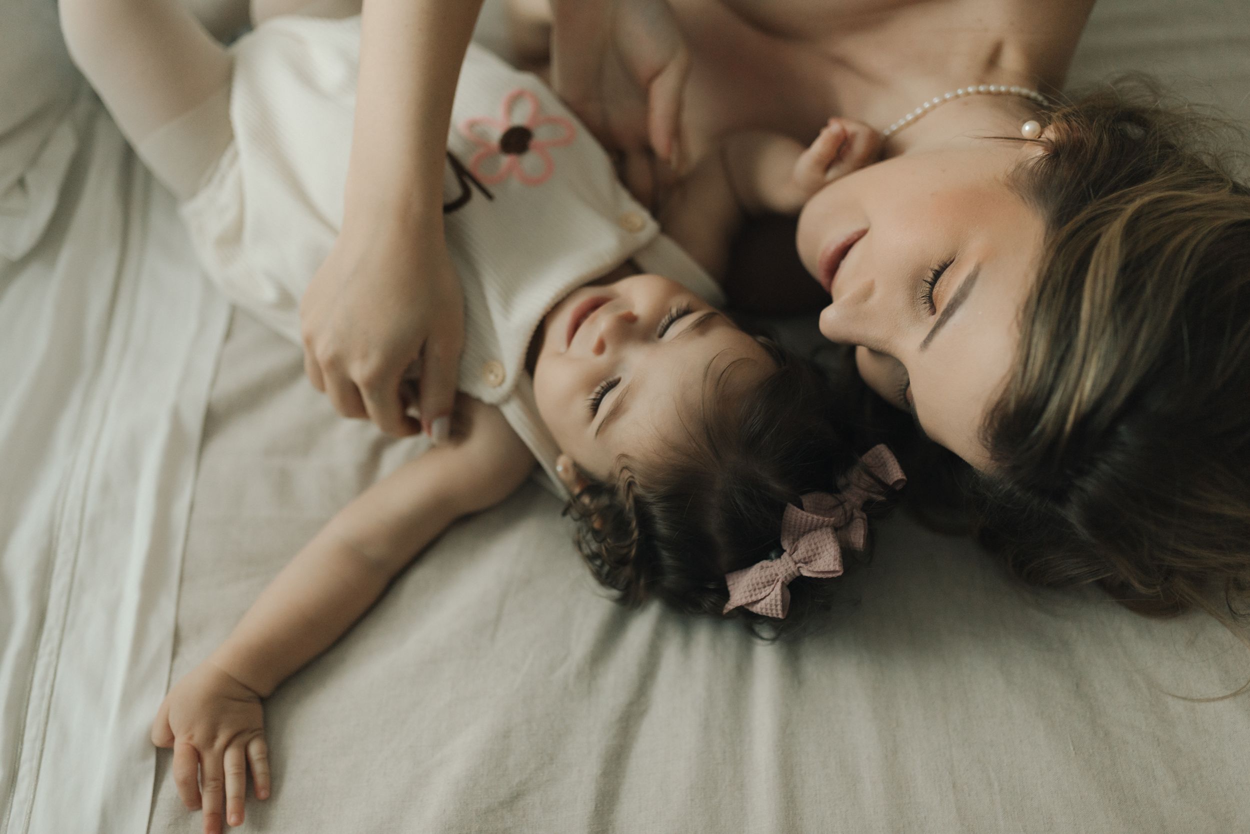 Two figures laying close together on white bedding in intimate moment.