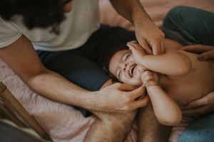 An intimate close-up shot of a giggling baby being tickled by gentle hands.