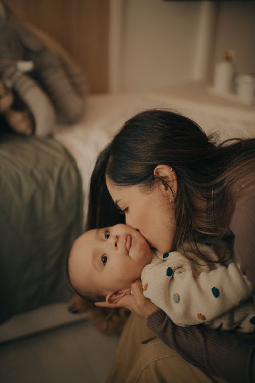 Tender moment between parent and baby in polka dot outfit.