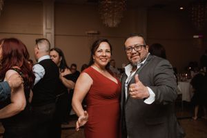 Couple in formal attire dancing and smiling at an indoor event.