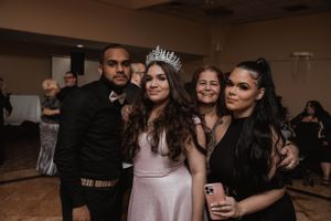 Group celebrating at formal event with person wearing crown in center.