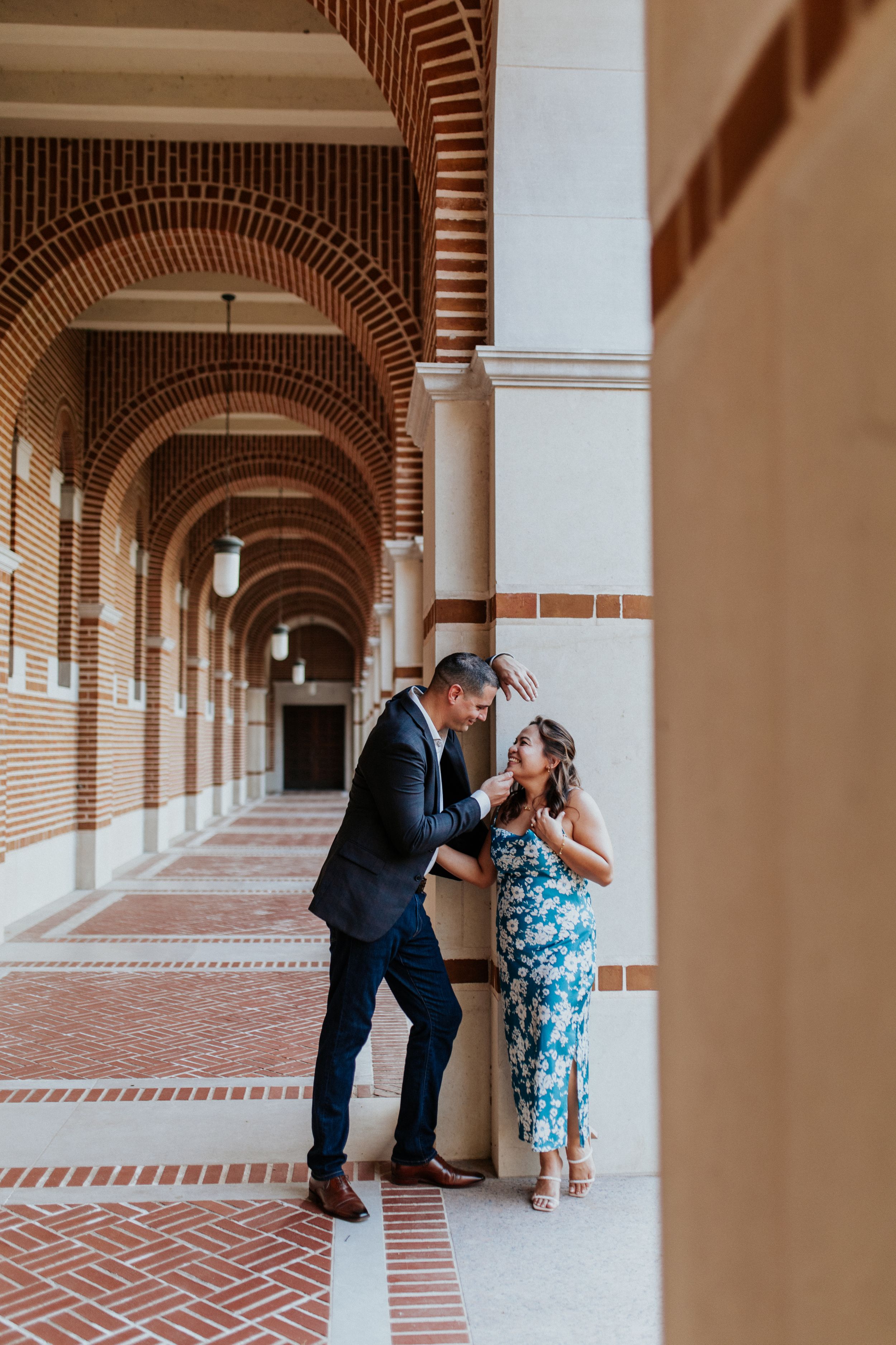 Couple shares intimate moments in an elegant arched hallway with brick and stone architectural details.