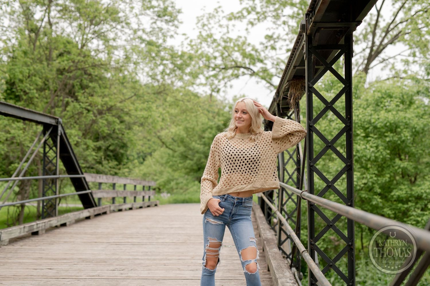 Casual outdoor portrait on vintage bridge featuring destroyed denim and knit sweater.