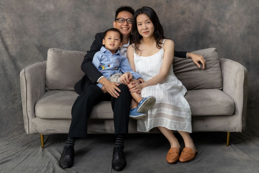 A cheerful family moment captured on a grey couch with casual and formal attire mixed.