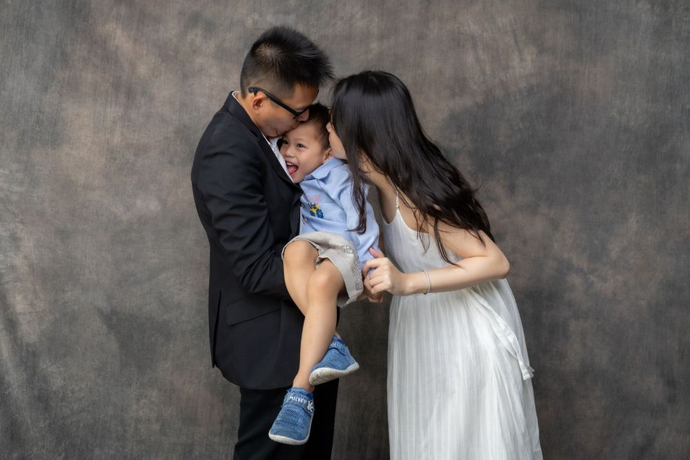 A family shares an intimate moment together against a dark gray backdrop.