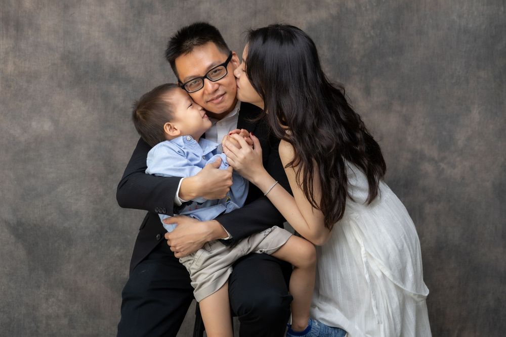 An affectionate family portrait showing parents embracing their young child.