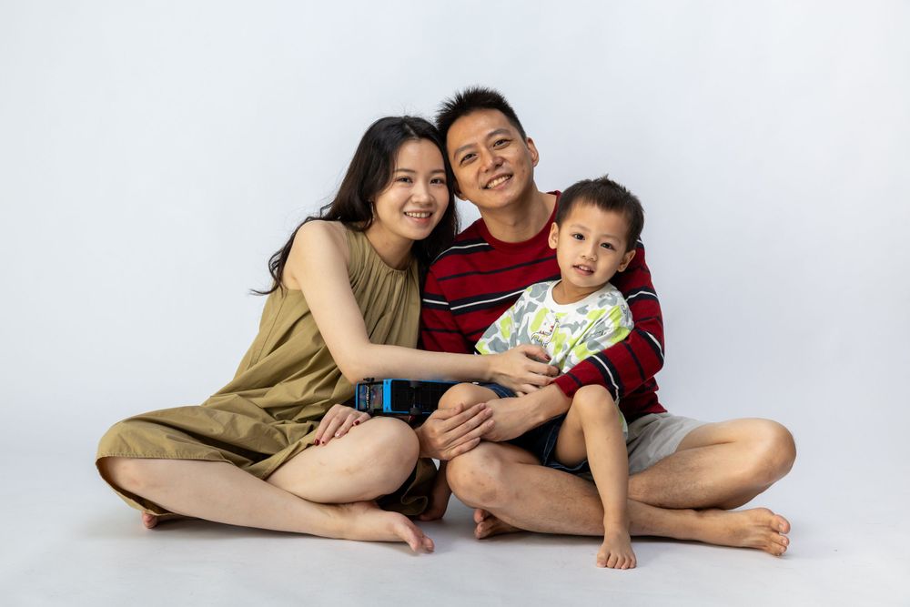 A relaxed family sitting together on the floor in a bright studio setting.