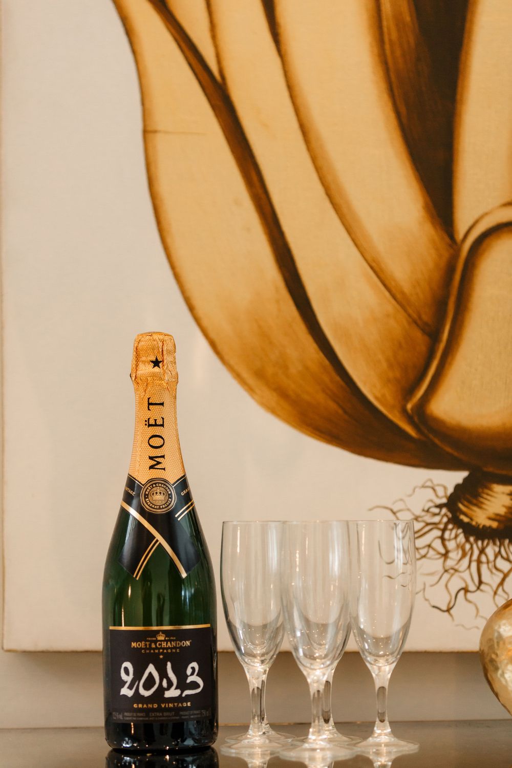 Moet champagne bottle and empty flutes arranged against artistic wall decor.