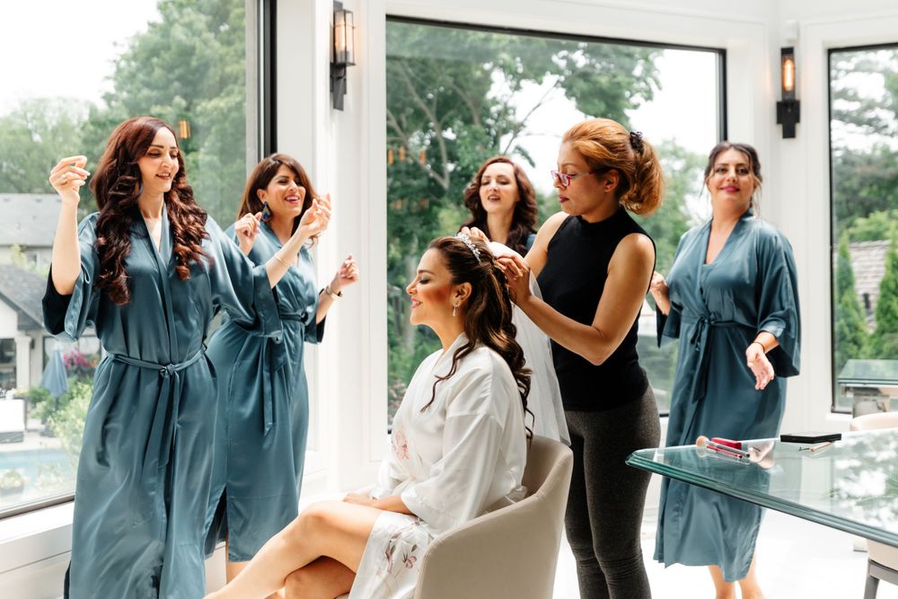 Wedding preparation scene with bridesmaids in blue robes helping with hair styling.