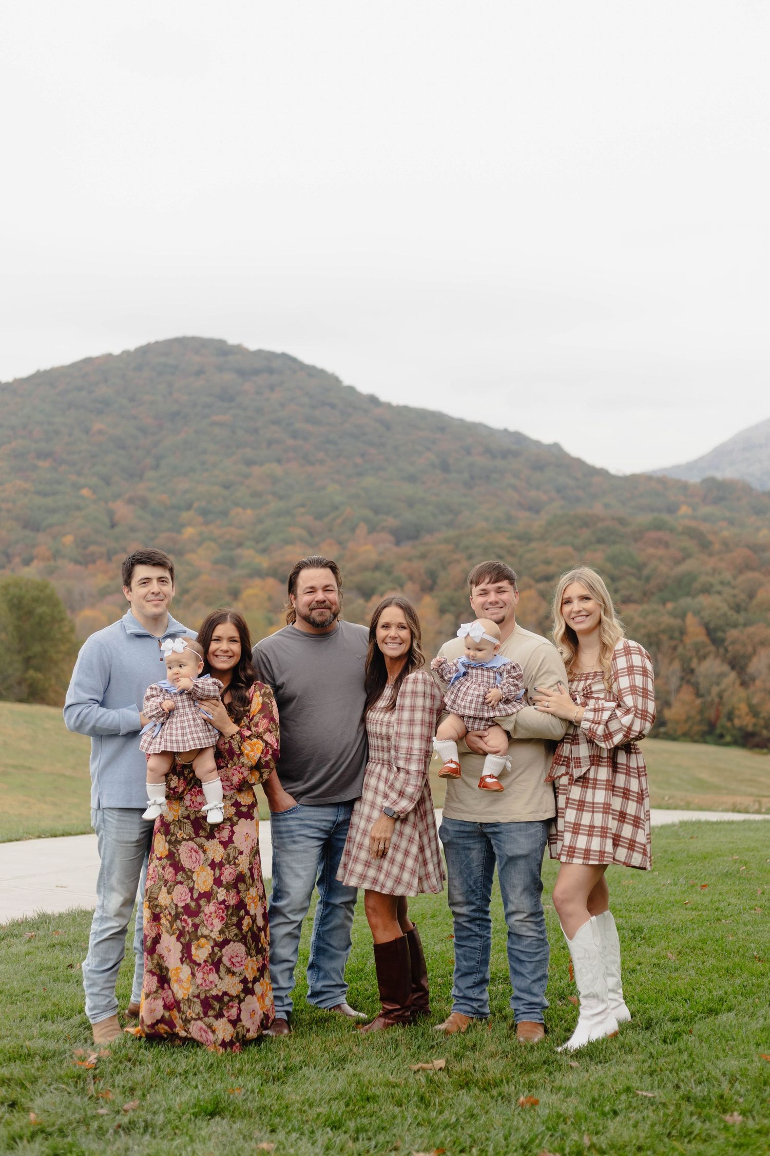 Family portrait of six people standing together against autumn mountain backdrop.