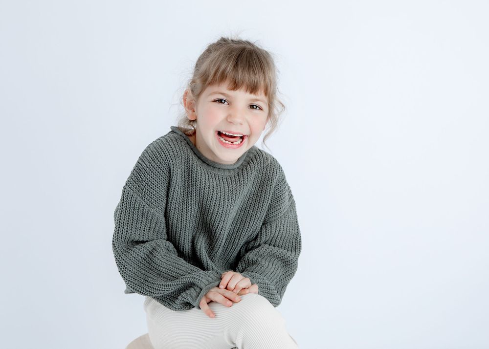 Candid moment captured wearing oversized gray sweater against clean white background.