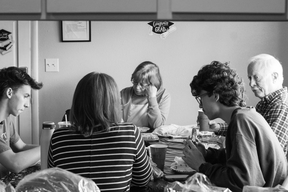 Group of people sharing a meal together at a table in black and white photography.