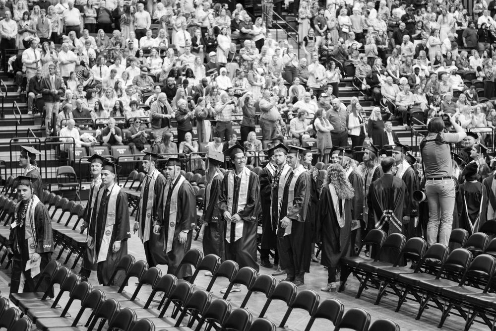 Black and white photo of graduates standing in rows during commencement ceremony.