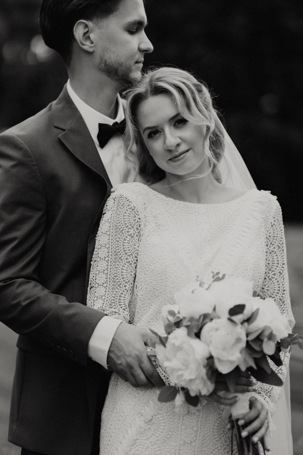 Romantic black and white portrait of newlyweds with white floral bouquet.